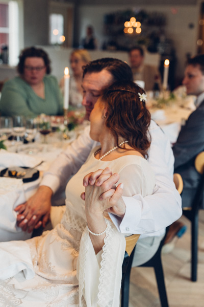 Hääpari lumoutuneena toisiinsa, taustalla häävieraita.